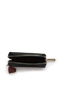 Portefeuille noir zippé avec des accessoires en ton doré, présentant un intérieur rouge et un petit charme en forme de cœur attaché à la tirette.