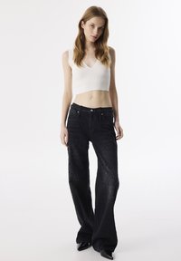 Zwarte denim broek met een textuurpatroon, met een hoge taille en wijde benen. Combineert met een aansluitend, geribbeld wit crop top.
