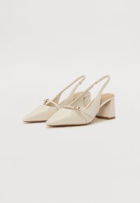 Beige lær slingback hæle med spids tå, blokhæl og guld accentdetalje over vamps. Glat overflade og moderne design.