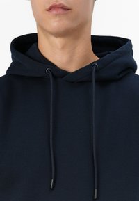 Mörkblå huvtröja med dragsko, med en mjuk yta och en åtsittande passform. Tyget verkar slätt utan synliga mönster.