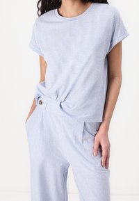 Blå och vit randig kortärmad t-shirt, lös passform med vikta ärmslut, knuten i midjan, ihop med matchande randiga byxor.