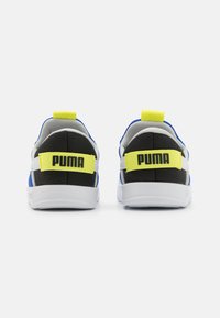 Des sneakers PUMA avec une tige principalement bleue, un talon noir, une semelle blanche et des sangles jaune vif avec un logo noir à l'arrière.