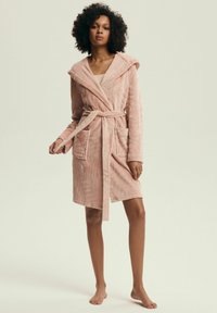 Miękki różowy szlafrok z teksturą, z kapturem, paskiem do wiązania i dwoma przednimi kieszeniami. Projekt o długości do połowy ciała, z delikatnym wzorem w paski.