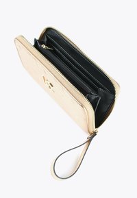 Portafoglio beige con zip e cinturino da polso, aperto per mostrare gli scomparti interni neri e la tasca con zip per carte e contanti.