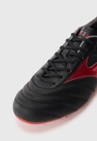 Pantofii de fotbal negri cu un superior din piele netedă, accente roșii, panouri texturate și șireturi negre. Au un vârf rotunjit și studuri pe talpă.