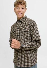 Camicia in flanella a scacchi marrone e beige con due tasche sul petto, chiusura con bottoni e maniche lunghe. Tessuto morbido con una vestibilità casual.