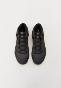 Czarne buty sportowe z siateczkową cholewką, gumową podeszwą i elastycznymi sznurówkami. Posiadają wzmocniony czubek i teksturowe detale po bokach.