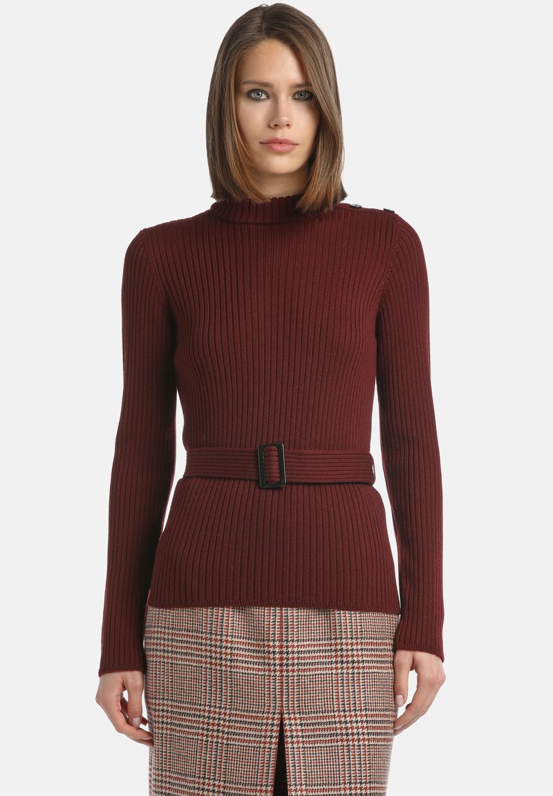 Pull en côtelé bordeaux avec un col montant, des manches longues et une coupe ajustée. Dispose d'une ceinture noire contrastante à la taille.