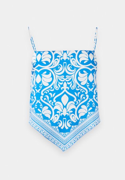 Blue patterned camisole top with white floral design, featuring thin shoulder straps and a triangular hem with intricate border detailing.