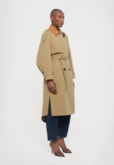 Bež trench coat, mille oranži krae, vööl, ja külgedel lõhed, koos tumesinine teksade ja kõrged kontsad.