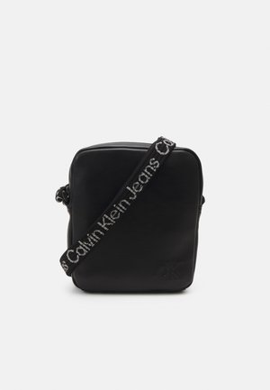 Borsa a tracolla in pelle nera con forma quadrata. Presenta una finitura testurizzata e una tracolla regolabile con logo "Calvin Klein Jeans".
