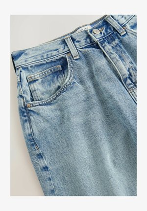 Jasnoniebieskie dżinsy z klasycznym pięciopocketowym wzorem, z wyblakłym wyglądem i widocznymi detalami przeszyć. Materiał ma miękką teksturę.