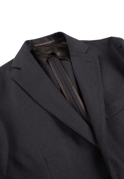 Ciemnoniebieska marynarka wykonana z teksturowanej tkaniny. Ma klapy z wycięciem, satynową podszewkę oraz plisowany tył.