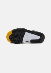 Černobílá podrážka sportovní obuvi s žlutými akcenty. Disponuje texturovanou gumou, vzorem pro lepší přilnavost a raženým logem.