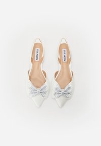Valkoiset kärjelliset slingback-kengät, joissa on teksturoitu nauha, jossa on hopeahohdetta, vaaleanruskeat pohjat ja matala korko, suunniteltu virallista käyttöä varten.