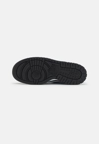 Suola di scarpa in gomma nera con motivo di battistrada testurizzato. Presenta design circolari e lineari per la trazione. Include dettagli con il logo Nike.