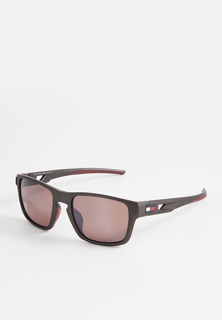 Schwarze rechteckige Sonnenbrillen mit rosa getönten Gläsern und kleinem rot-weiß-blauem Logo an den Bügeln.