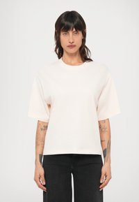 Camiseta oversize de color rosa claro con mangas cortas y cuello redondo, confeccionada en suave algodón. Presenta un ajuste holgado.