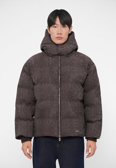 Giacca a vento in marrone scuro con un motivo intricato, grande cappuccio, zip frontale completa e polsini elastici, caratterizzata da una silhouette squadrata.