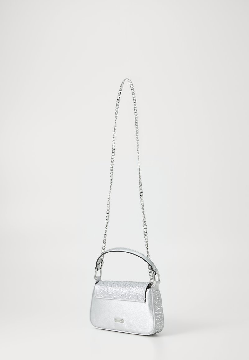 Petit sac à main argenté avec rabat clouté, poignée courte sur le dessus et longue bandoulière chaîne sur fond uni clair.