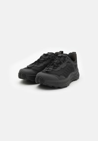 Zwarte sportieve schoenen met een textuur bovenwerk, een versterkte neuskap en een rubberen buitenzool met diepe groeven voor grip. Vetersluiting voor een veilige pasvorm.