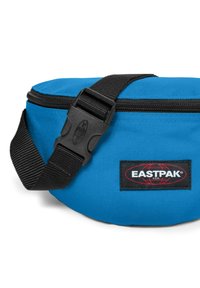 Borsa in nylon blu con una cintura regolabile nera, dotata di una fibbia in plastica e di un patch del logo Eastpak rosso e nero sul lato.