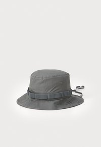 Grey bucket hat made of lightweight fabric. Features a wide brim, structured top, adjustable strap, and subtle stitching details.