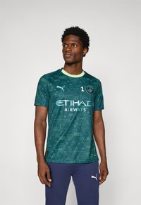 Groen patroon voetbalshirt met korte mouwen, voorzien van een ronde halslijn, "ETIHAD Airways"-logo en een klein embleem op de borst.
