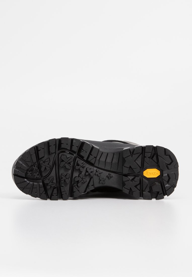Schwarze Wanderschuhsohle mit robustem Design, tiefen Profilen, Vibram-Branding und einer strukturierten Musterung für verbesserten Halt.