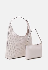 Deux sacs à main : un grand tote perforé de couleur rose clair avec une petite pochette lisse assortie, dotée d'une fermeture éclair et d'une fine anse.