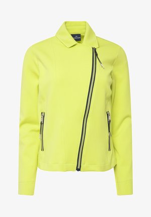 Lys gul jakke med skræddersyet krave, asymmetrisk frontlynlås og to sidelommer med lynlås i kontrasterende mørkeblå farve. Blødt, glat stof.