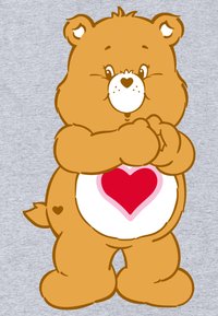 Karakterbamse med en rund krop, orange pels og en hvid mave med et pink hjerte. Den har et smilende ansigt og små ører.