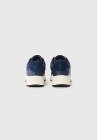Navy blue sneakers with a textured upper, soft suede accents, and a contrasting off-white sole. Features a rounded shape and padded collar.