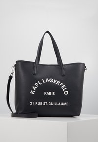 Czarna skórzana torba na ramię z dwoma uchwytami, odczepianym paskiem na ramię oraz białym tekstem Karl Lagerfeld Paris z adresem z przodu.