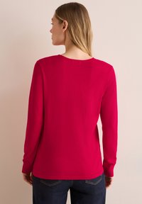 T-shirt à manches longues en rose vif, avec un col rond et une coupe décontractée, fabriqué en tissu léger avec un léger stretch.