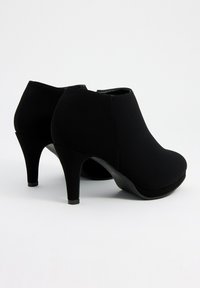 Botines negros de tacón alto con textura lisa, puntera redondeada y tacón afilado. El material parece sintético sin acentos visibles.