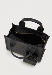 Μαύρη δερμάτινη τσάντα με διπλές λαβές, ανοιχτή με φερμουάρ στην κορυφή και μικρή προσαρτημένη θήκη σε ουδέτερο φόντο.