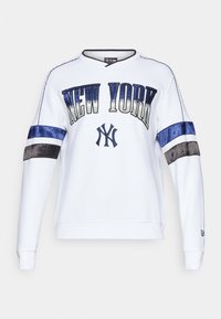 Balta džempera krekls ar uzrakstu "NEW YORK" uzrakstīts resnām burtiem, Yankees emblēma un krāsu bloku satīna piedurknes tumši zilā un pelēkā krāsā.