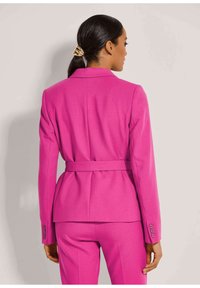 Taillierter pinker Blazer mit einem Gürtel in der Taille, strukturierten Schultern und geknöpften Manschetten. Glattes Material mit einem maßgeschneiderten Design und minimalen Details.
