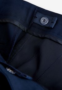 Fascia in tessuto blu navy con chiusura a bottone; l'interno presenta una fodera liscia e cuciture ordinate; il tessuto appare resistente e morbido.