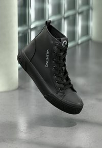 Μαύρα ψηλά αθλητικά παπούτσια με λείο δερμάτινο εξωτερικό, σχέδιο με κορδόνια, λογότυπο και υφασμένο καουτσούκ σόλα.