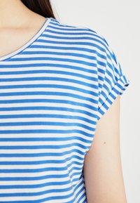 Haut à rayures bleues et blanches à manches courtes avec un col arrondi, doté de manches roulées et d'une texture douce en coton.