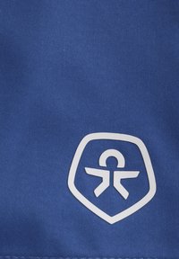 Blauwe stof met een gladde textuur toont een wit schildlogo met daarop een persoon met uitgestrekte armen, gecentreerd in het ontwerp.