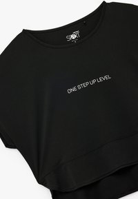 Top atletico nero cropped con maniche corte e scollatura rotonda. La scritta "ONE STEP UP LEVEL" è stampata in bianco sul davanti.