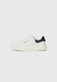 Hvite lær sneakers med svart hælaccent og logo. Har rund tå, flat såle og perforeringer for pusteevne.