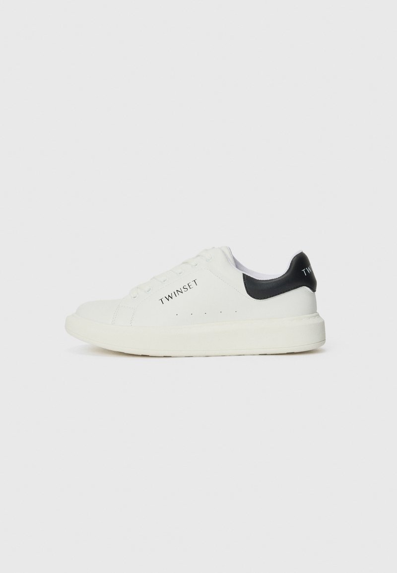 Hvite lær sneakers med svart hælaccent og logo. Har rund tå, flat såle og perforeringer for pusteevne.