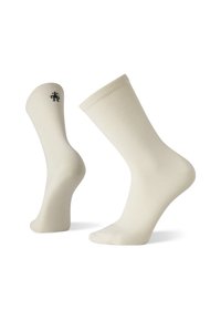 Knielange, cremefarbene Socken aus einem weichen, dehnbaren Material mit einem gerippten Rand und einem kleinen, dunklen Logo an der Seite.