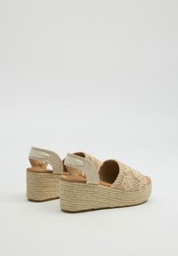 Sandalias de cuña beige con parte superior de ganchillo, correa elástica en el tobillo y tacón de yute trenzado. Diseño de punta abierta con detalles de bordado floral.