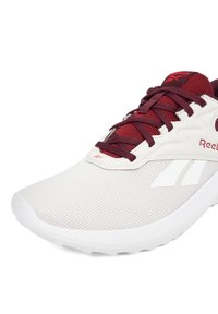 White athletic shoe with mesh upper, maroon accents, and gray detailing. Features laces, reinforced toe, and textured sole for grip.