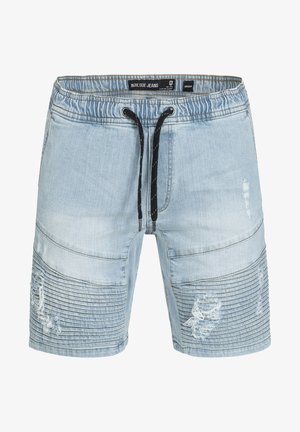 Világoskék farmer sort, rugalmas derékpánttal, fekete húzózsinórral és kopott területekkel, amelyek oldalán bordázott részletek találhatók.